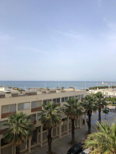 un bâtiment avec des palmiers en face de l'océan dans l'établissement T 1 VUE MER 180 D° TEMPLE DU SOLEIL, à La Grande Motte