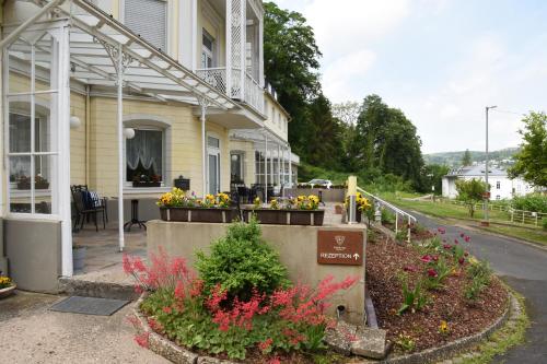 a house with a flower garden in front of it at Trip Inn Parkhotel Bad Ems in Bad Ems