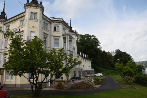 a large white building with a tree in front of it at Trip Inn Parkhotel Bad Ems in Bad Ems