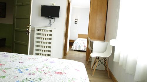 a bedroom with a bed and a tv on the wall at Hostal Orejas in León