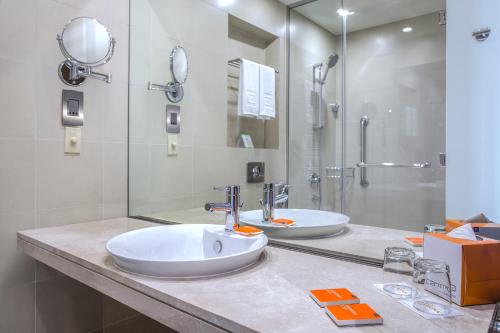 沙迦的住宿－Centro Sharjah，一间带两个盥洗盆和淋浴的浴室