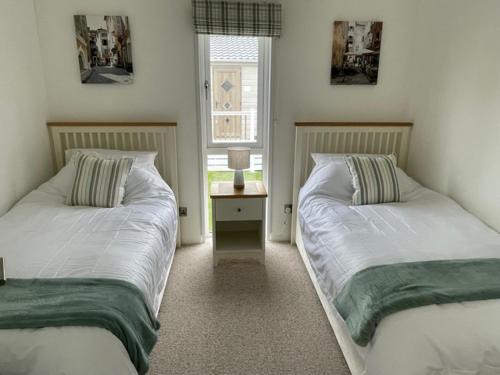 2 camas individuales en un dormitorio con ventana en Tuscany Lodge, en Merston