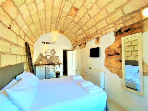 a bedroom with a white bed with a stone ceiling at Da Lorenza di Casa Camilla Journey in Depressa