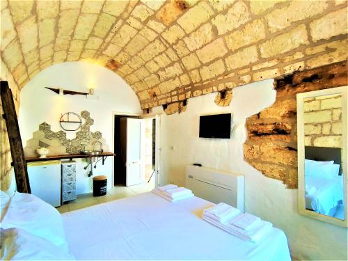 a bedroom with a white bed and a stone wall at Da Lorenza di Casa Camilla Journey in Depressa