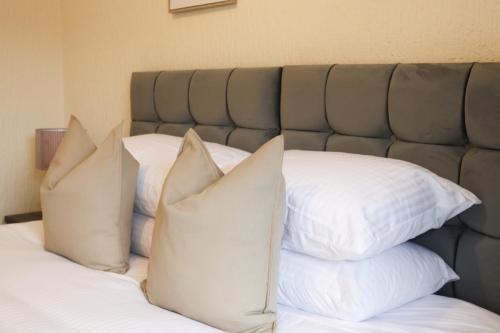 a pile of pillows sitting on top of a bed at Cosy Ardrossan Apartment in Ardrossan