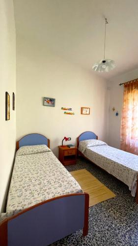 a bedroom with two beds and a table and a window at Villa Assunta in Tertenìa