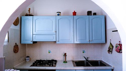 a kitchen with blue cabinets and a sink at Villa Assunta in Tertenìa