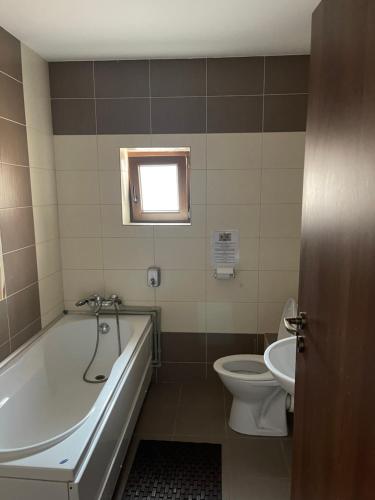 a bathroom with a tub and a toilet and a sink at Vila cu trandafiri - Cozy Apartments Studio cu pat matrimonial in Bragadiru