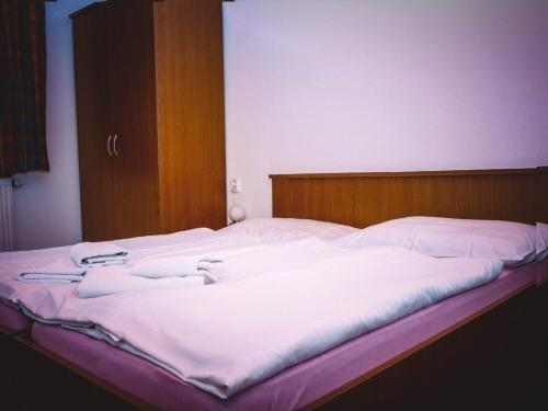 a large bed with white sheets and a wooden headboard at Penzion u Hajneho Bedricha in Harrachov