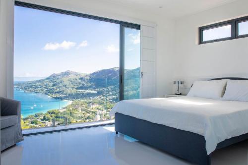 a bedroom with a large window with a view of the ocean at Paradise Heights Luxury Apartments & Villa in Beau Vallon