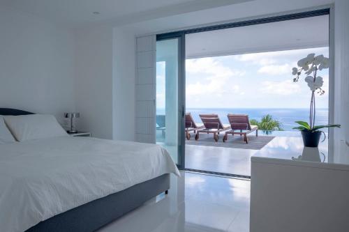a bedroom with a bed and a view of the ocean at Paradise Heights Luxury Apartments & Villa in Beau Vallon