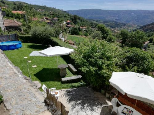 a garden with a table and umbrellas on the grass at Casa das Lages in Viariz