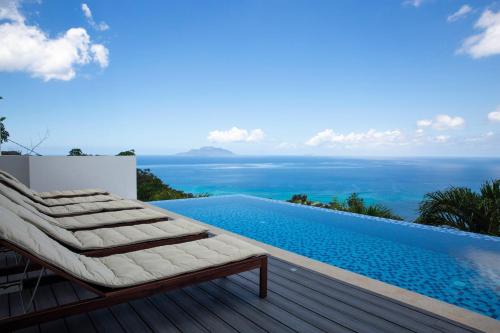 a pool with a chaise lounge next to a swimming pool at Paradise Heights Luxury Apartments & Villa in Beau Vallon