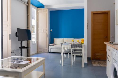 un soggiorno con tavolo e parete blu di Mar y Arte Apartamentos a Málaga
