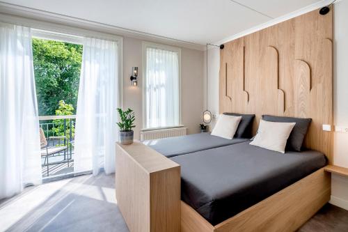 a bedroom with a bed with a wooden headboard and a window at Hotel Villa Vida in Domburg