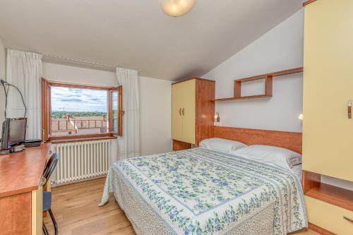 a bedroom with a bed and a desk and a window at La Quiete B&B in Lovrečica