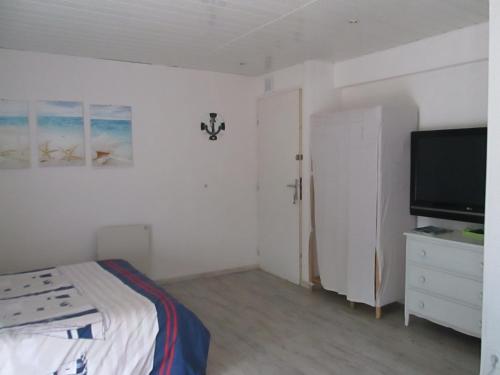 1 dormitorio con 1 cama y TV de pantalla plana en A 350m de la plage, en Fouesnant