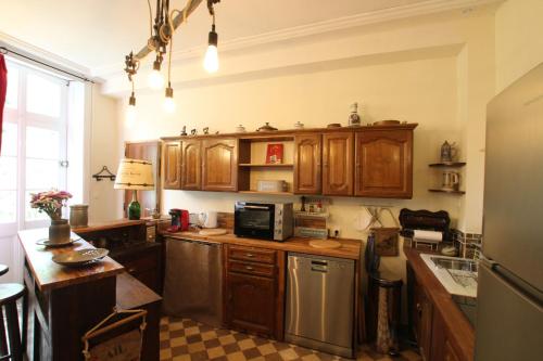 une cuisine avec des armoires en bois et des appareils en acier inoxydable dans l'établissement Le Presbytère, Cotentin, Val de Saire, Fermanville, proximité immédiate mer et forêt, à Fermanville