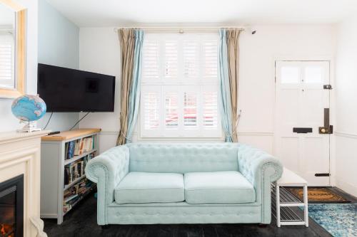 uma sala de estar com um sofá azul e uma televisão em Shakespeare House Town Centre FREE Parking em Stratford-upon-Avon