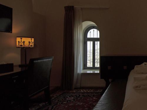 a bedroom with a window and a bed and a chair at The Sephardic House Hotel in The Jewish Quarter in Jerusalem