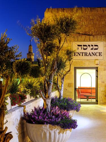 a large white planter with purple flowers in front of a store at The Sephardic House Hotel in The Jewish Quarter in Jerusalem
