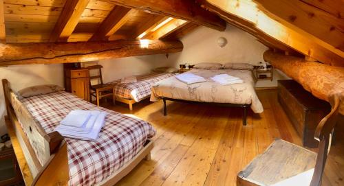 a attic room with two beds and wooden floors at Casa Ornella - Baita Pra Sec in Montita