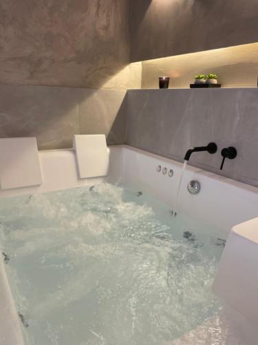 a bath tub filled with water with a sink at Jacuzzi Suite Ladadika in Thessaloniki