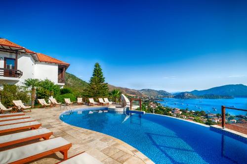 a swimming pool with chairs and a view of the water at Les Terrasses De Selimiye in Selimiye