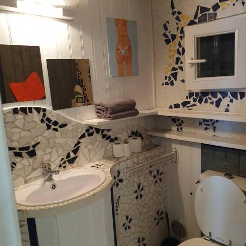 une salle de bain avec un lavabo et des toilettes dans l'établissement La Maison Mosaic Medoc - Gîtes, à Gaillan-en-Médoc