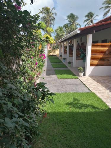 a walkway next to a building with grass and flowers at Casa Grande in Camocim
