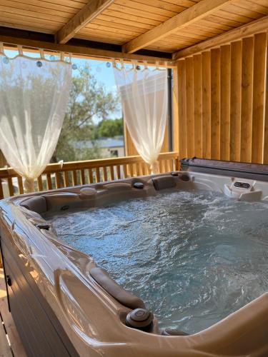 a hot tub in a wooden house with curtains at Rosmarin&Olive Premium Mobile Homes in Selce