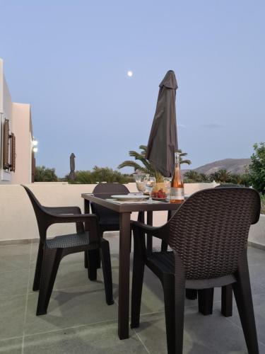 stół z 2 krzesłami i parasol na patio w obiekcie Olivar Suites w mieście Palekastron