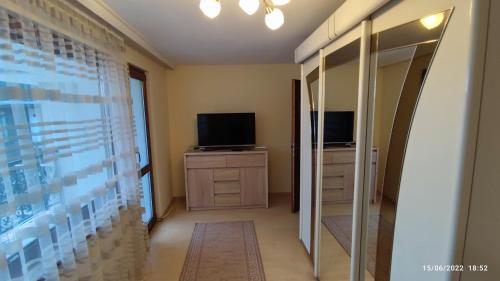 Zimmer mit einem TV und einer Kommode mit einem Spiegel in der Unterkunft апартамент Росен in Nessebar