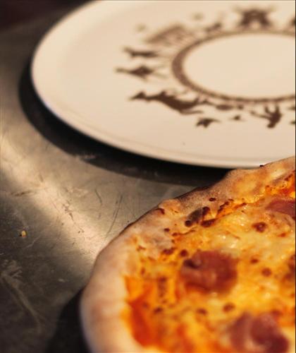 a pizza sitting on a table next to two plates at Hotel Browar Kościerzyna in Kościerzyna