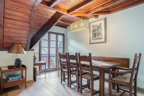 a dining room with wooden ceilings and a table and chairs at Luderna - Tríplex Nin C2 Arenho in Naut Aran