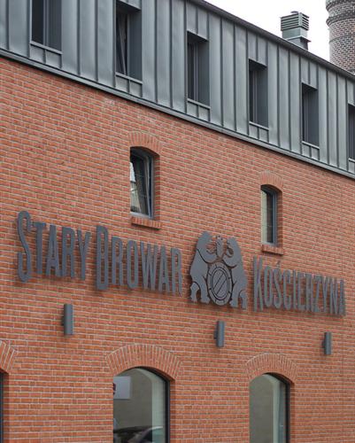 a brick building with a sign on the side of it at Hotel Browar Kościerzyna in Kościerzyna
