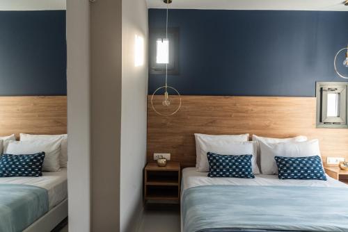 two beds in a room with blue walls at Muse by the beach with Jakuzzi in Amoudara Lasithiou