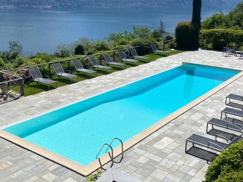 een groot blauw zwembad met stoelen en de oceaan bij Residenza Parco Sant Andrea in Menaggio