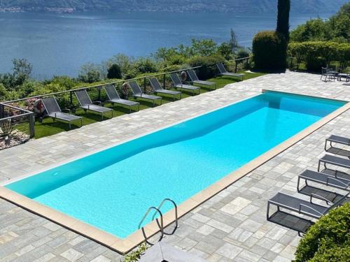 a large blue swimming pool with chairs and the ocean at Residenza Parco Sant Andrea in Menaggio