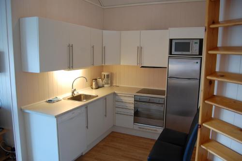 una cucina con armadi bianchi e frigorifero in acciaio inossidabile di Hamresanden Resort as a Kristiansand