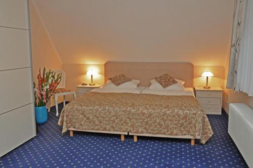a hotel room with a bed and two tables and two lamps at Hotel Garni Kristinenhof in Bad Zwischenahn