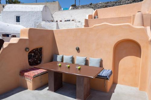 a small patio with a wooden table and pillows at Azalea Houses in Oia