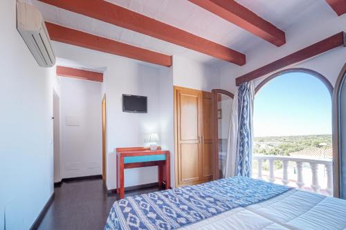 a bedroom with a bed and a balcony with a window at Castell de Lô in Cala en Porter