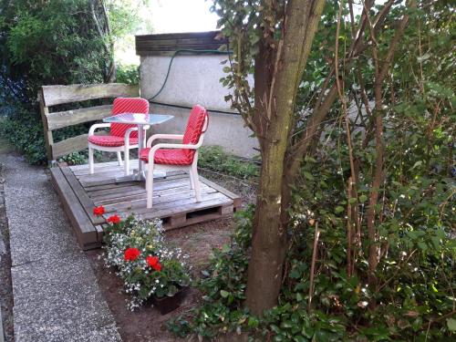 duas cadeiras vermelhas e uma mesa num banco de madeira em Antikhüttchen em Kalletal