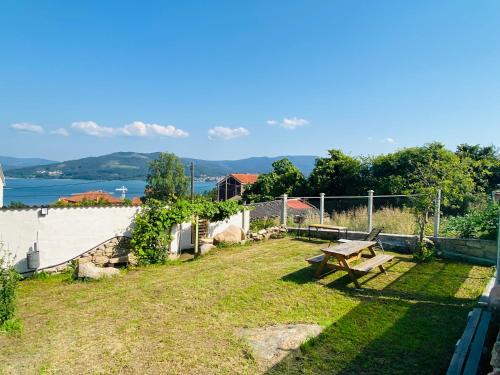 einen Hinterhof mit Picknicktisch und Blick auf das Wasser in der Unterkunft Balcón de Braño in O Freixo