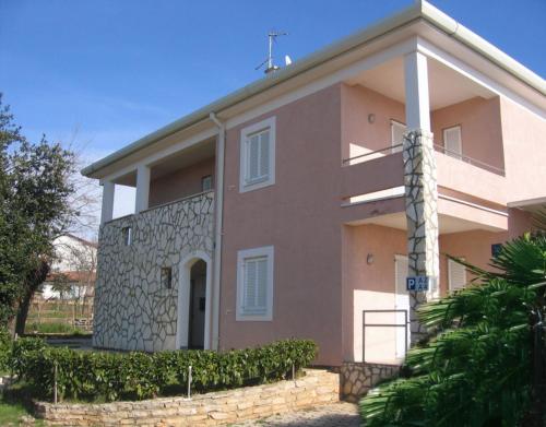 een groot roze huis met een stenen muur bij Apartments Fuchs in Umag