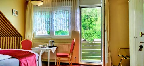 Schlafzimmer mit einem Bett, einem Tisch und einem Fenster in der Unterkunft Pension Ramona - Hotel Garni in Bad Soden-Salmünster