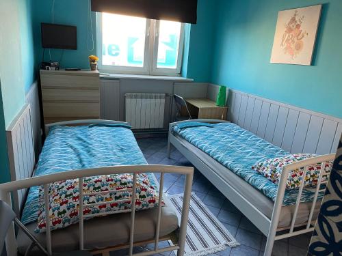 two beds in a room with blue walls at U Jana in Przemyśl