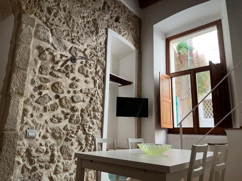 una sala da pranzo con un tavolo e un muro di pietra di La Rupe Apartments Tropea a Tropea