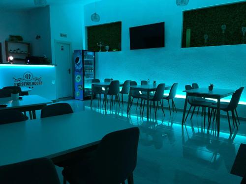 a dining room with tables and chairs and blue lighting at Pensiunea Prestige House in Curtea de Argeş